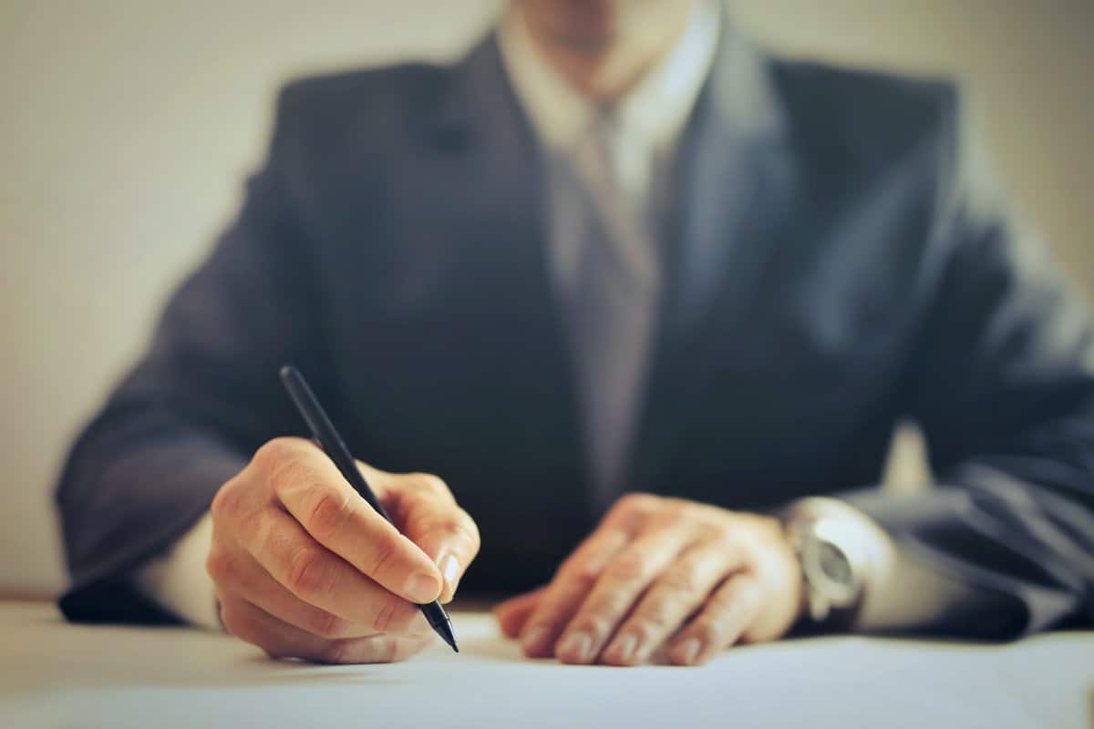 A person at a desk signing a paper.