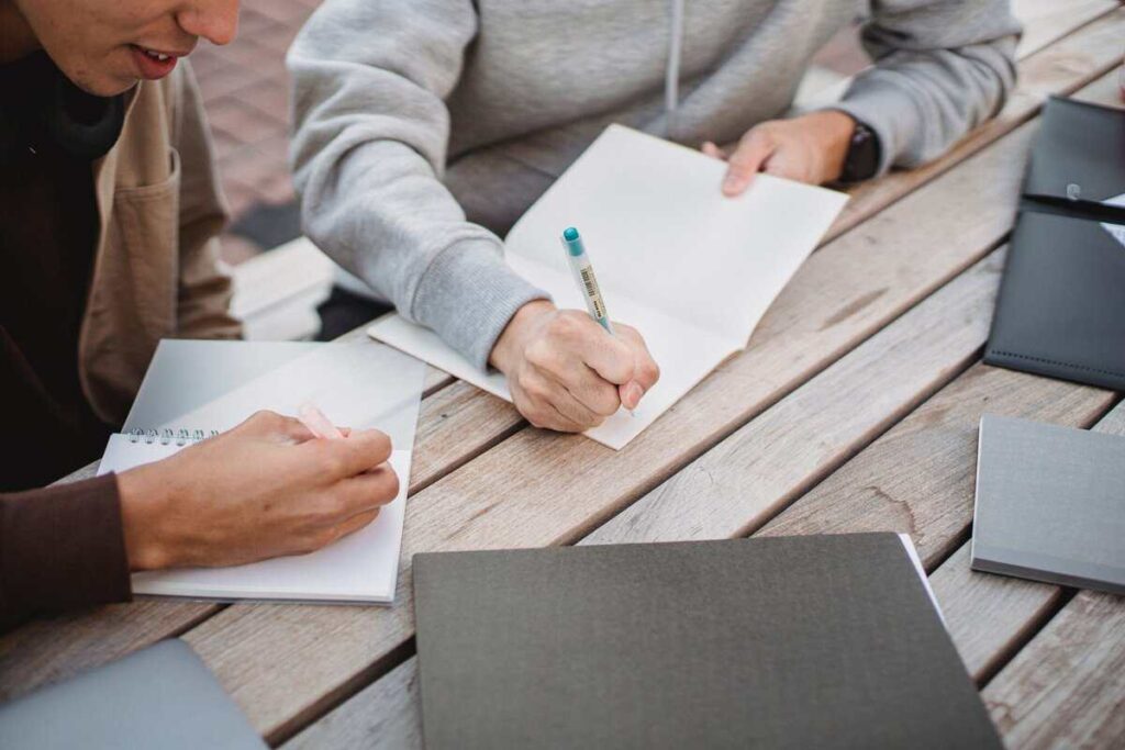 Two people at a desk writing notes.
