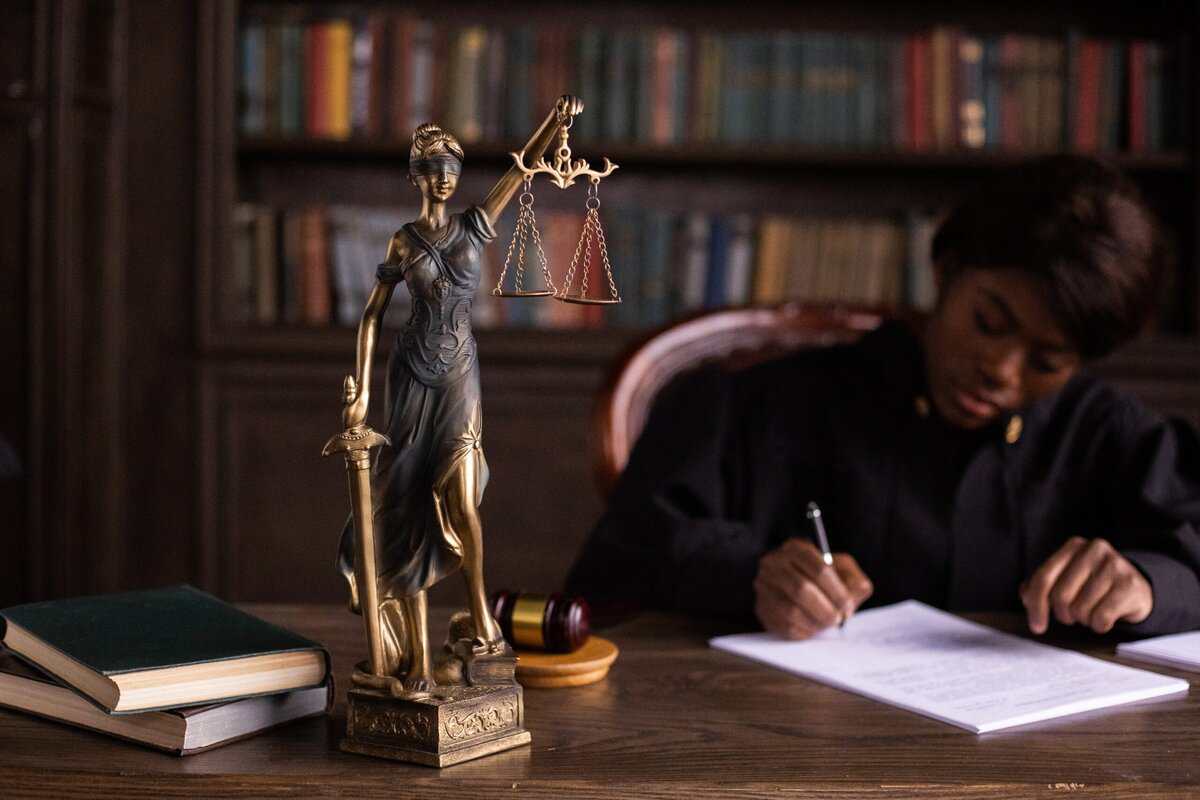 A person sitting at a desk reviewing a document, a justice statute in front.