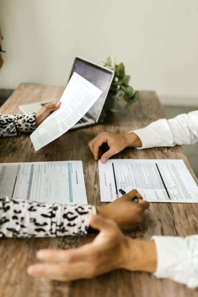 Two people sitting across each other reviewing papers.