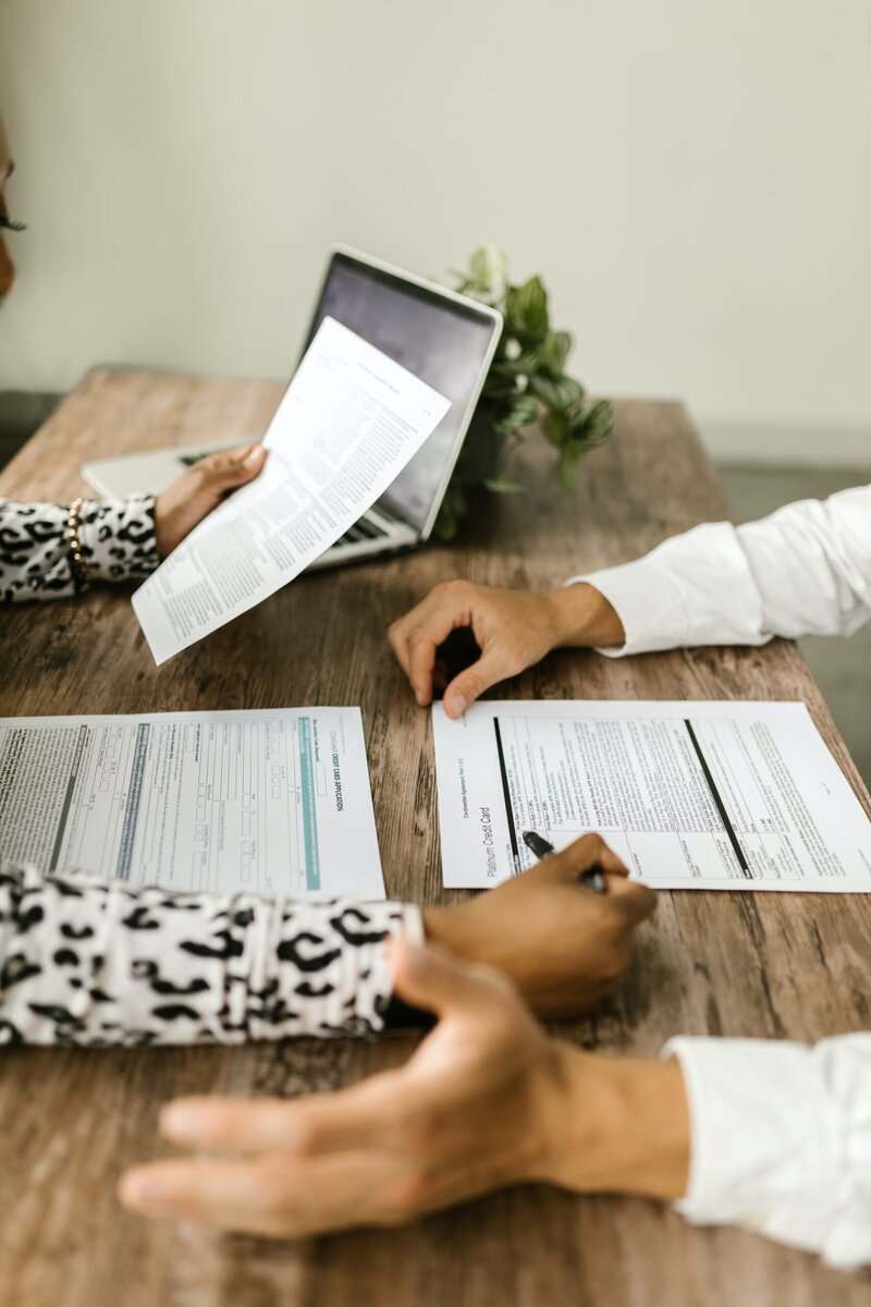 Two people sitting across each other reviewing papers.