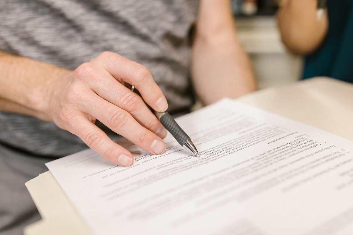 A person holding a pen to a document.