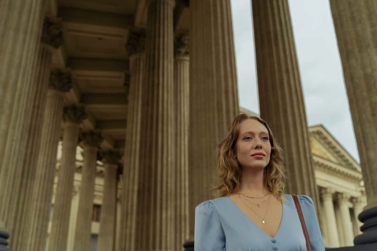 A person walking through a columned path.