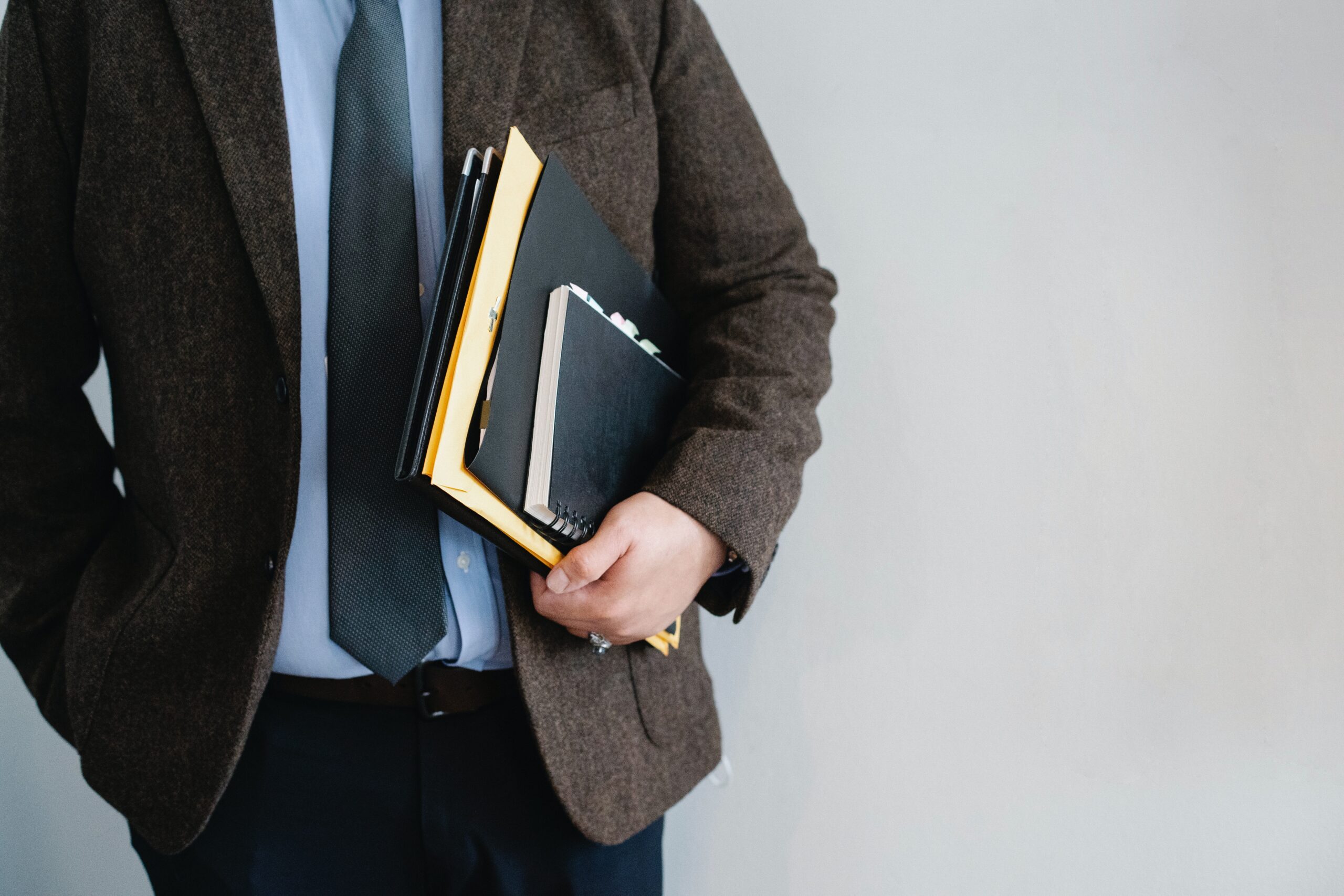 A person walking while holding folders and notepads.