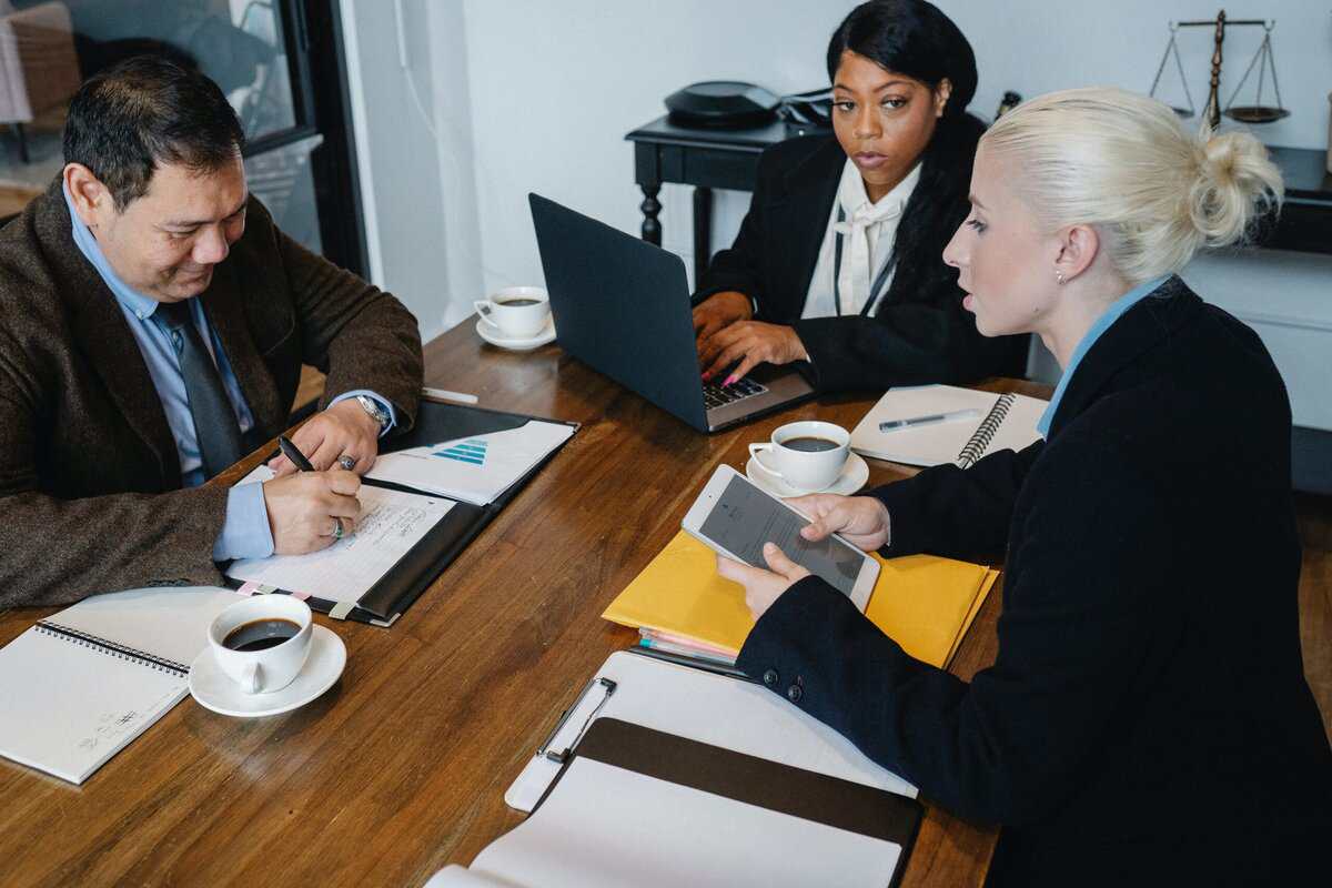 Three people around a table reviewing documents.