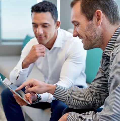 Two men is dress shirts seated discussing documents