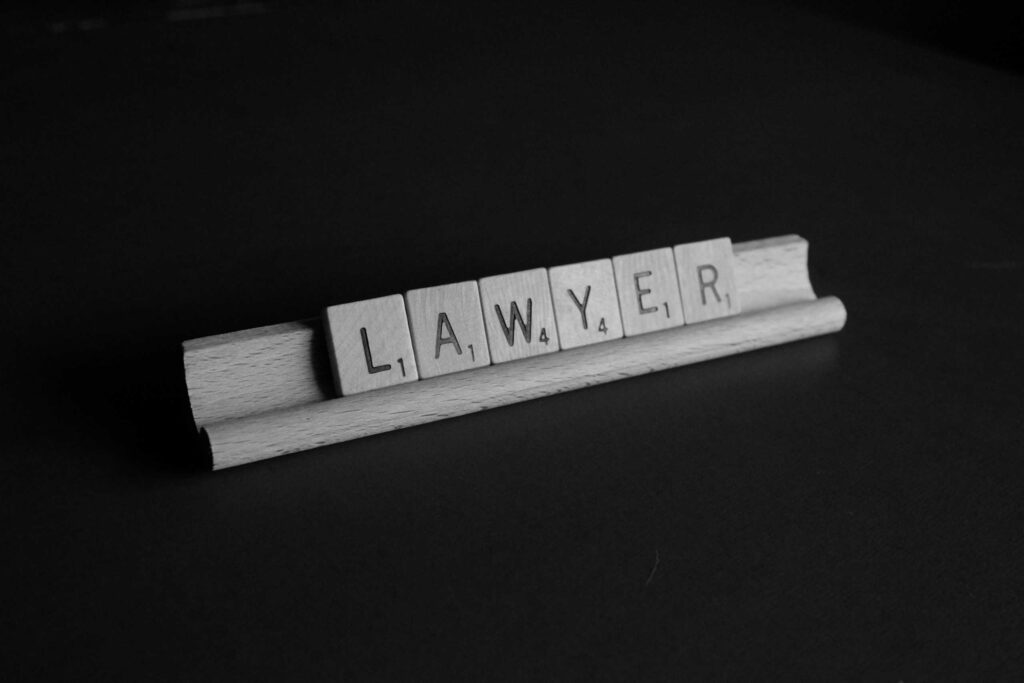 letter tiles from Scrabble game spell out "Lawyer" on holder